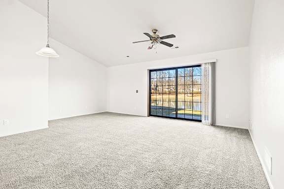 A spacious living room with a ceiling fan and a sliding glass door leading to a patio at Tanglewood Apartments, Oak Creek, WI