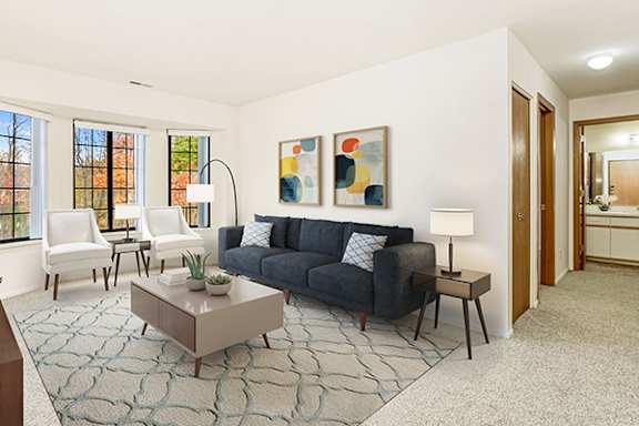 A living room with a bay window, a grey couch, and a coffee table Bay window in living room at Tanglewood Apartments, Oak Creek