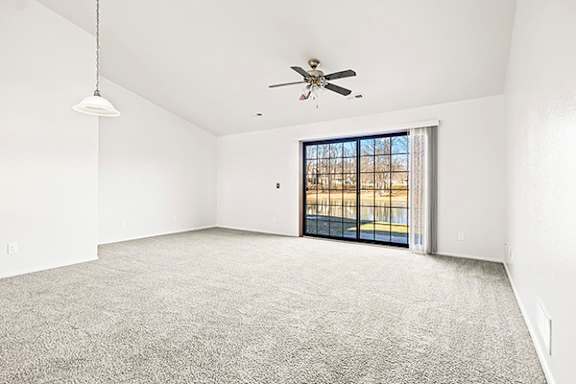 A spacious living room with a ceiling fan and a sliding glass door leading to a patio at Tanglewood Apartments in Oak Creek, WI