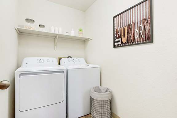 A laundry room with a washer and dryer and a shelf above at Tanglewood Apartments, Wisconsin, 53154