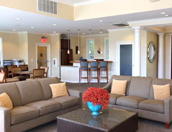A living room with a grey couch and a blue vase with red flowers on a coffee tableat LakePointe Apartments, Ohio, 45103