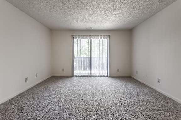 an empty living room with a sliding glass door to a balcony at The Timbers Apartments, Evansville, IN