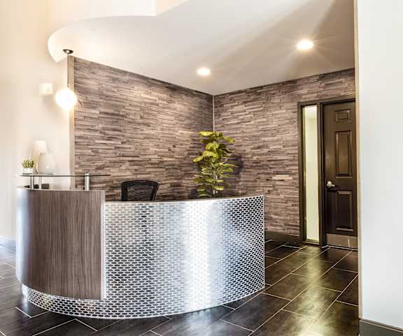 a curved reception desk in a hotel lobby with a brick wall at The Timbers Apartments, Evansville, Indiana