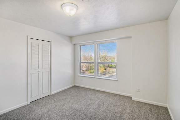 A bedroom with a large window and a door to a walk-in closet at Tracy Creek Apartments, Ohio