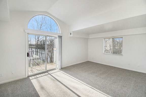 A living room with a cathedral ceiling, carpeted floor and a large arched window at Tracy Creek Apartments, Ohio