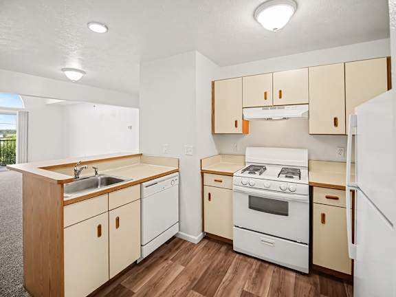 A kitchen with white appliances, wooden cabinets and a breakfast bar at Tracy Creek Apartments, Ohio