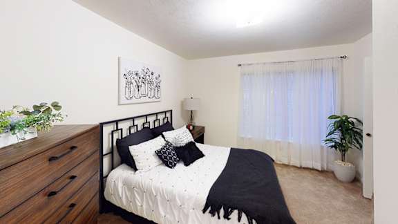 A bedroom with a bed, nightstand, and a potted plant at Tracy Creek Apartment Homes, Perrysburg, OH, 43551