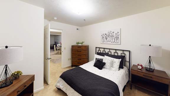 A bedroom with a bed, nightstand, and lamp at Tracy Creek Apartment Homes, Perrysburg, OH, 43551