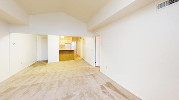 A spacious living room with a cathedral ceiling and plush carpet at Tracy Creek Apartment Homes in Perrysburg, OH