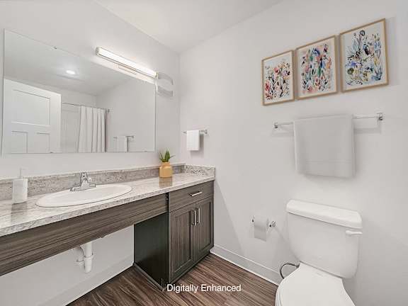 a bathroom with a toilet and a sink and a mirror at Trade Winds Apartment Homes, Elkhorn, NE