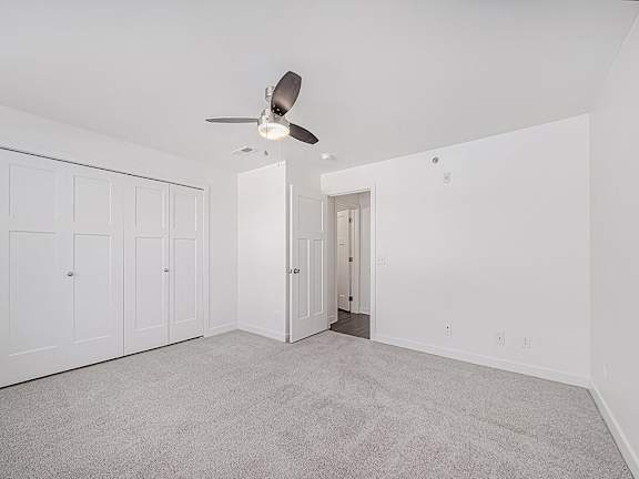 A bedroom with a ceiling fan and carpeted floor at Trade Winds Apartment Homes, Elkhorn, NE