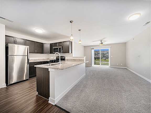 A kitchen with a refrigerator, microwave, and a countertop with a sink at Trade Winds Apartment Homes, Elkhorn, NE