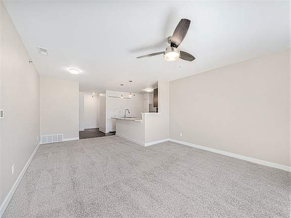 A living room with a ceiling fan and carpeted floor at Trade Winds Apartment Homes, Elkhorn, NE