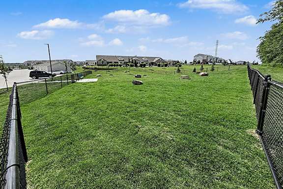 A large grassy dog park with a fence surrounding it at Trade Winds Apartment Homes in Elkhorn, NE