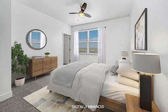 A bedroom with a bed, a ceiling fan, and a potted plant at Trade Winds Apartment Homes in Elkhorn, NE