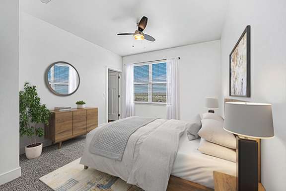 A bedroom with a bed, a ceiling fan, and a potted plant at Trade Winds Apartment Homes in Elkhorn, NE
