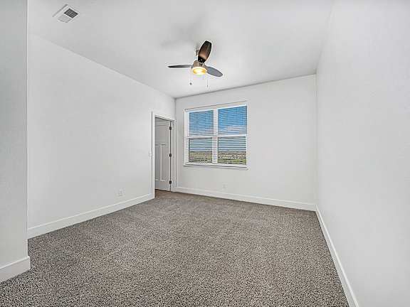 A bedroom with a ceiling fan and a window with blinds at Trade Winds Apartment Homes, Elkhorn, NE