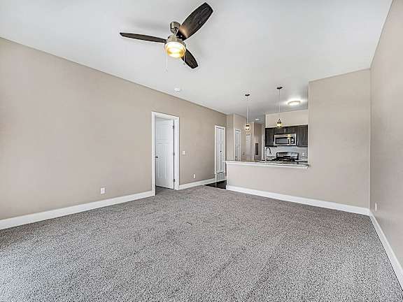 A living room with a ceiling fan and carpeted floor at Trade Winds Apartment Homes, Elkhorn, NE