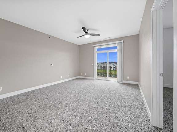 A living room with a 9' ceiling and a ceiling fan at Trade Winds Apartment Homes, Elkhorn, NE