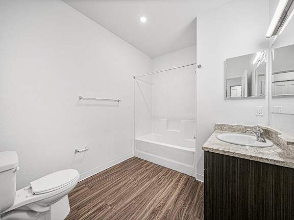A white toilet sits next to a sink in a bathroom at Trade Winds Apartment Homes, Elkhorn, NE