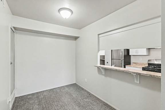 A dining room with a grey carpet and a breakfast bar at Trappers Cove Apartments, Lansing