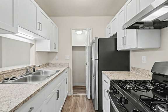 A kitchen with stainless steel appliances, a pantry and white appliances at Trappers Cove Apartments, Lansing