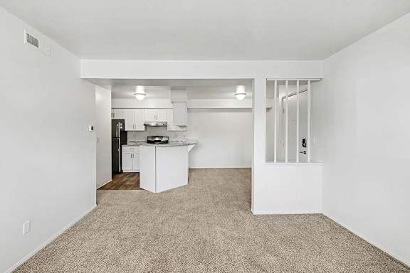 A kitchen with white cabinets, stainless steel appliances and a dining room at Trappers Cove Apartments, Lansing