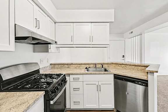 A kitchen with a stainless steel gas stove and dishwasher at Trappers Cove Apartments, Lansing