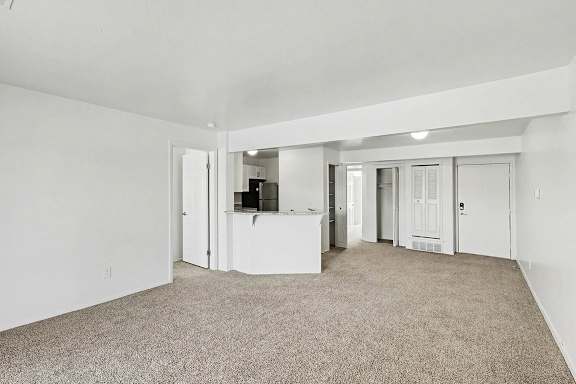 A spacious living room with carpeted floor and white walls at Trappers Cove Apartments, Lansing