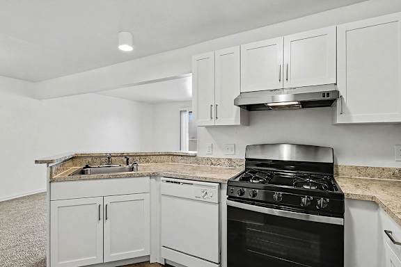 A kitchen with a stainless steel gas stove, dishwasher, a white cabinets at Trappers Cove Apartments, Lansing