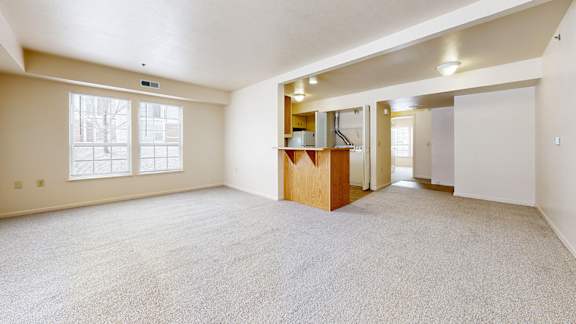 A spacious dining room with a carpeted floor and a breakfast bar at Trillium Pointe Apartment Homes, Michigan, 49201
