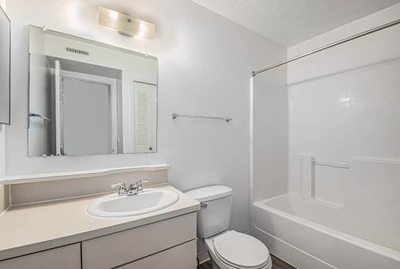 A white bathroom with a toilet, sink, and bathtub at Trillium Pointe Apartment Homes, Michigan, 49201