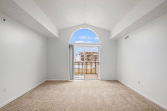 A spacious living room with a cathedral ceiling and a view of a balcony at Trillium Pointe Apartment Homes, Michigan, 49201
