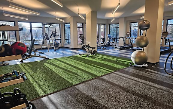 A gym with a green artificial turf floor and various exercise equipment