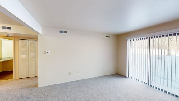 the spacious living room has a large window with blinds at Walnut Trail Apartments, Portage