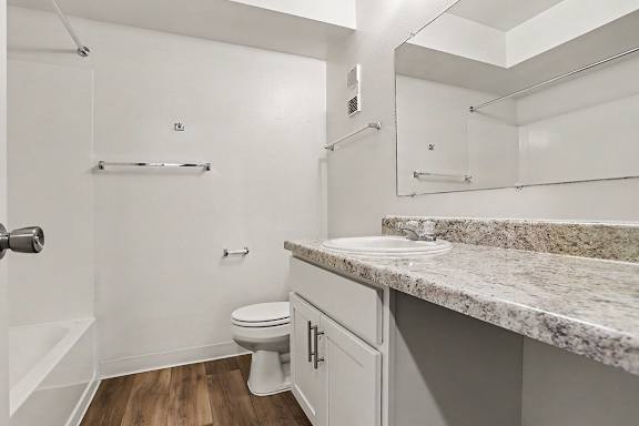 A white bathroom with a large counter top and a toilet at Walnut Trail Apartments, Michigan