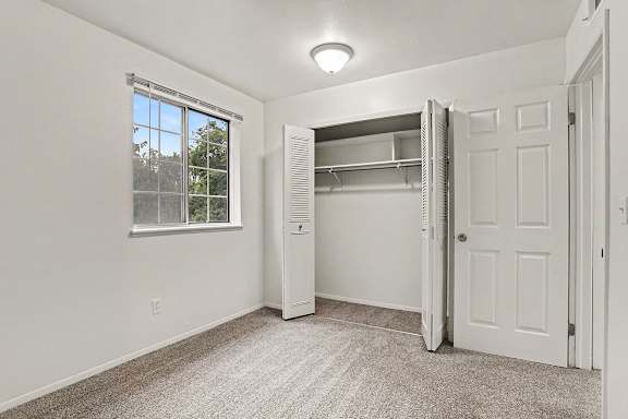A white bedroom with a window and a closet at Walnut Trail Apartments, Michigan