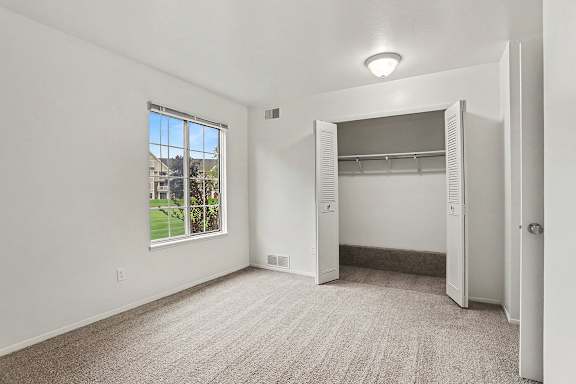 A spacious bedroom with a large window and a closet at Walnut Trail Apartments, Michigan