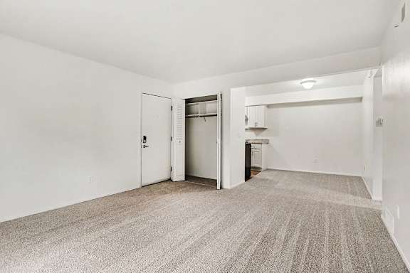 A living and dining room with a carpeted floor and a closet at Walnut Trail Apartments, Michigan