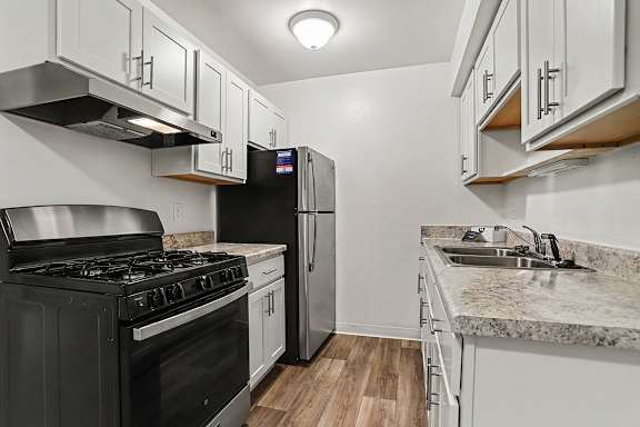 An upgraded kitchen with stainless steel appliances and white cabinets at Walnut Trail Apartments, Michigan