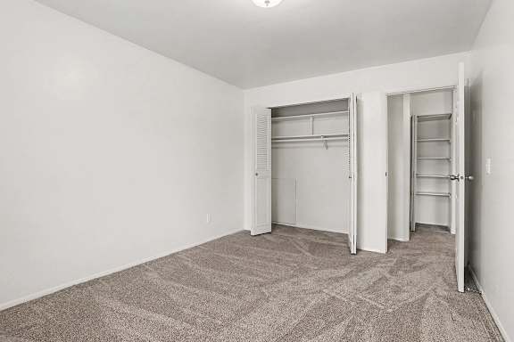 Bedroom with dual closets and carpet flooring at Walnut Trail Apartments, Portage, MI 49002