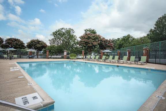 A large swimming pool surrounded by a fence and lounge chairs at WaterFront Apartments, Virginia Beach