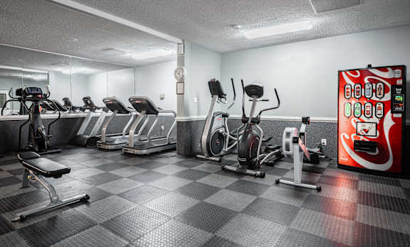 A gym with a variety of exercise equipment including treadmills, stationary bikes, and weight machines at WaterFront Apartments, Virginia Beach