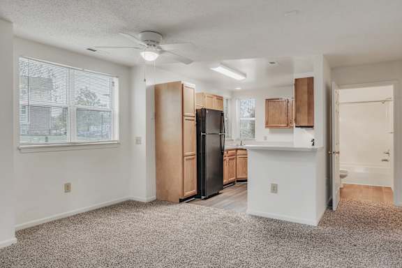 A spacious kitchen with wooden cabinets and a black refrigerator at WaterFront Apartments, Virginia Beach