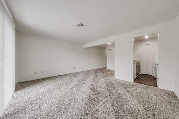 A large, empty room with a carpeted floor and white walls at WaterFront Apartments, Virginia Beach