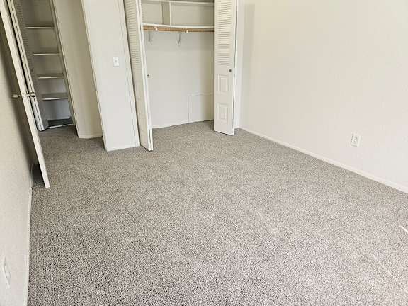 A bedroom with a carpeted floor and a closet at Waverly Park Apartments, Lansing