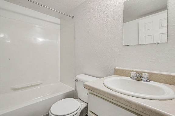 A white toilet sits next to a sink in a bathroom at Waverly Park Apartments, Lansing, Michigan