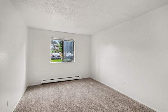 A bedroom with a window and a carpeted floor at Waverly Park Apartments, Lansing, Michigan