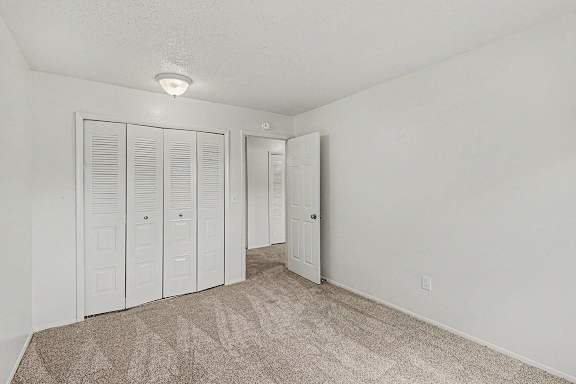 A bedroom with white walls and a carpeted floor with a large white closet at Waverly Park Apartments, Lansing, Michigan