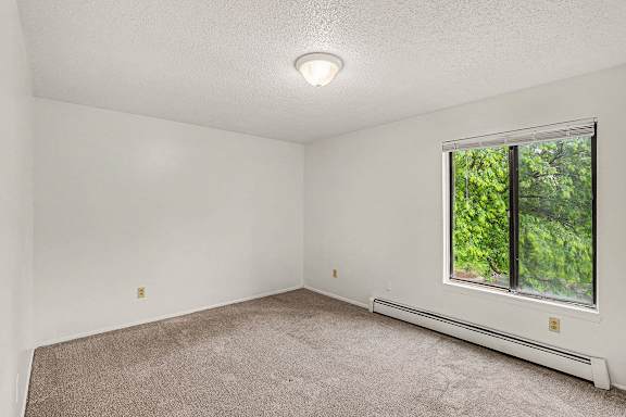 A bedroom with a large window at Waverly Park Apartments, Lansing, Michigan